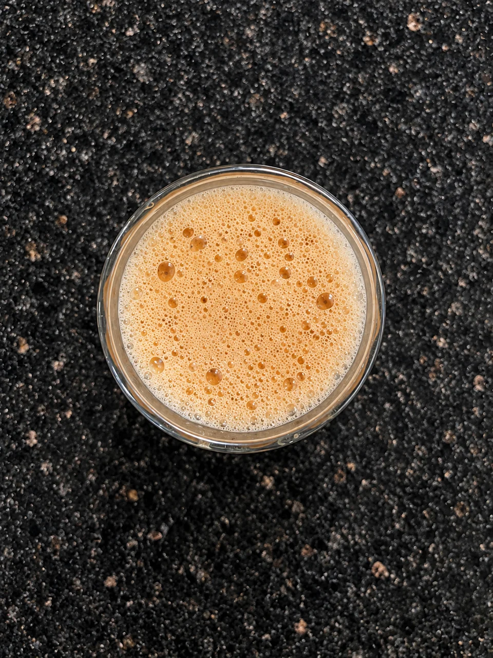 A glass of frothy milk tea on the restaurant table.