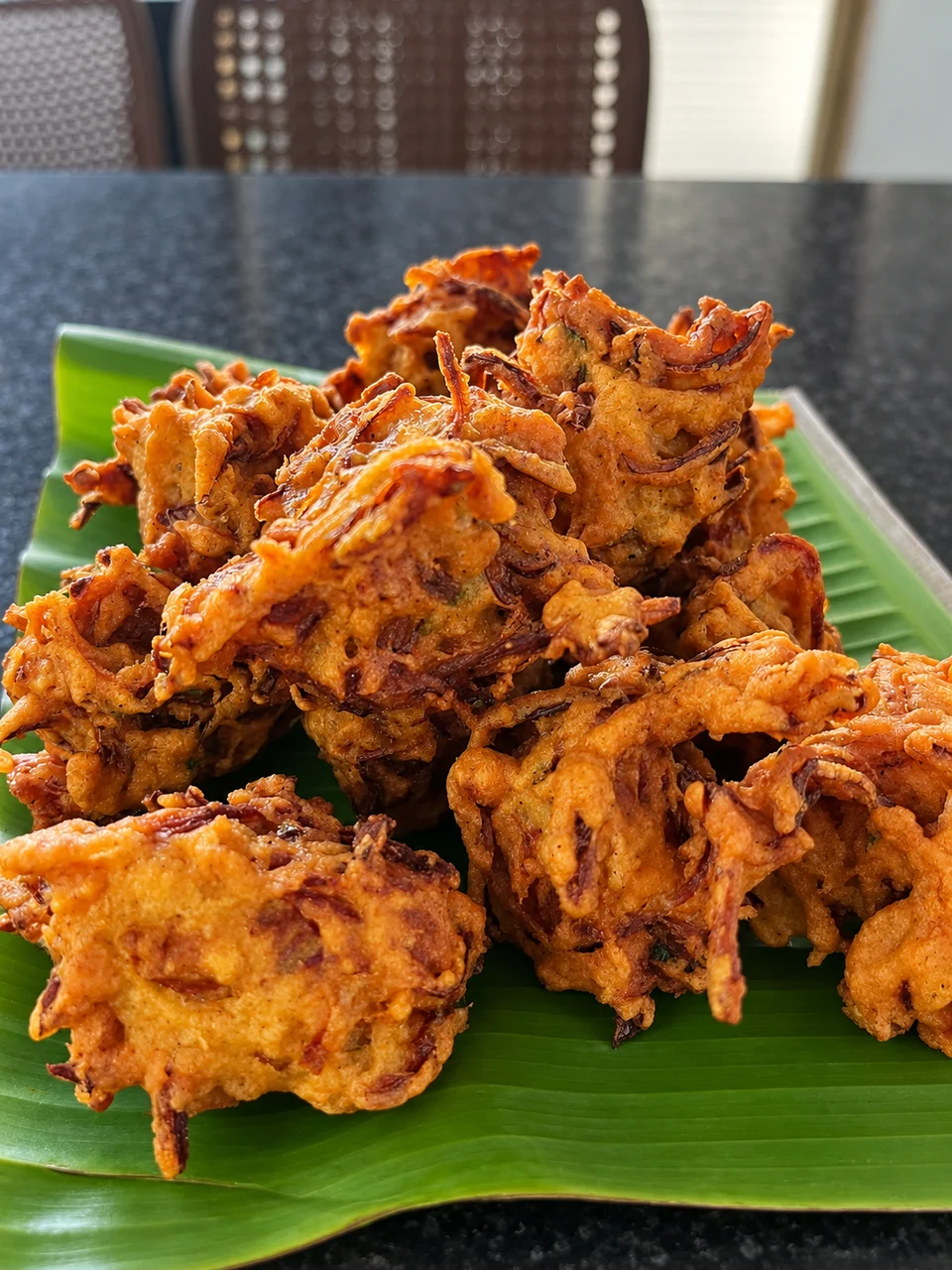 Golden onion pakoda served on a banana leaf.